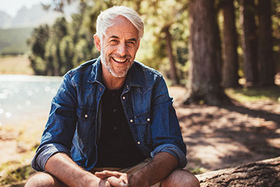 Older Man with teeth porcelain veneers Smiling By A Lake